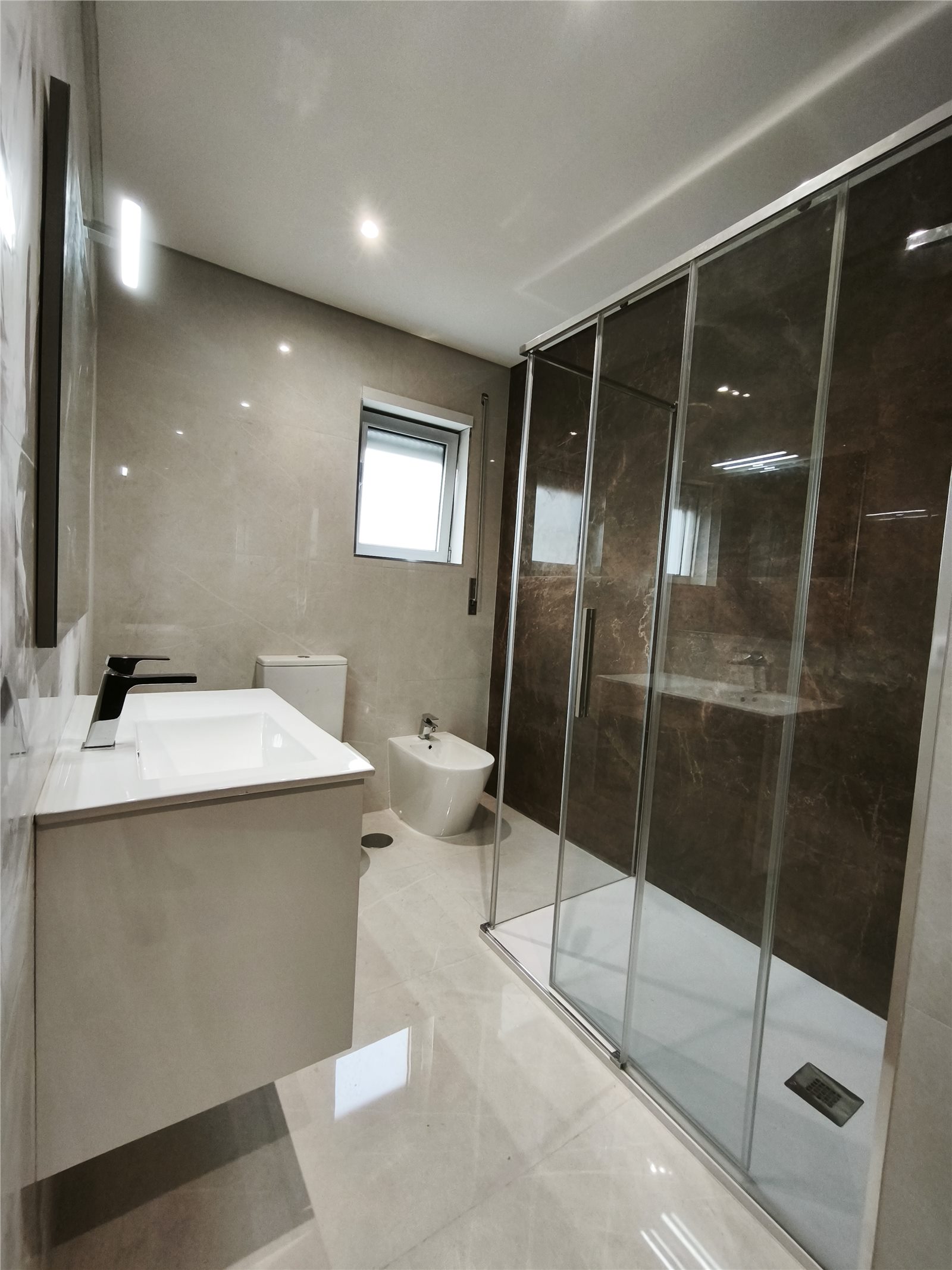 Casa de banho renovada com revestimento cerâmico, duche em vidro e móvel suspenso