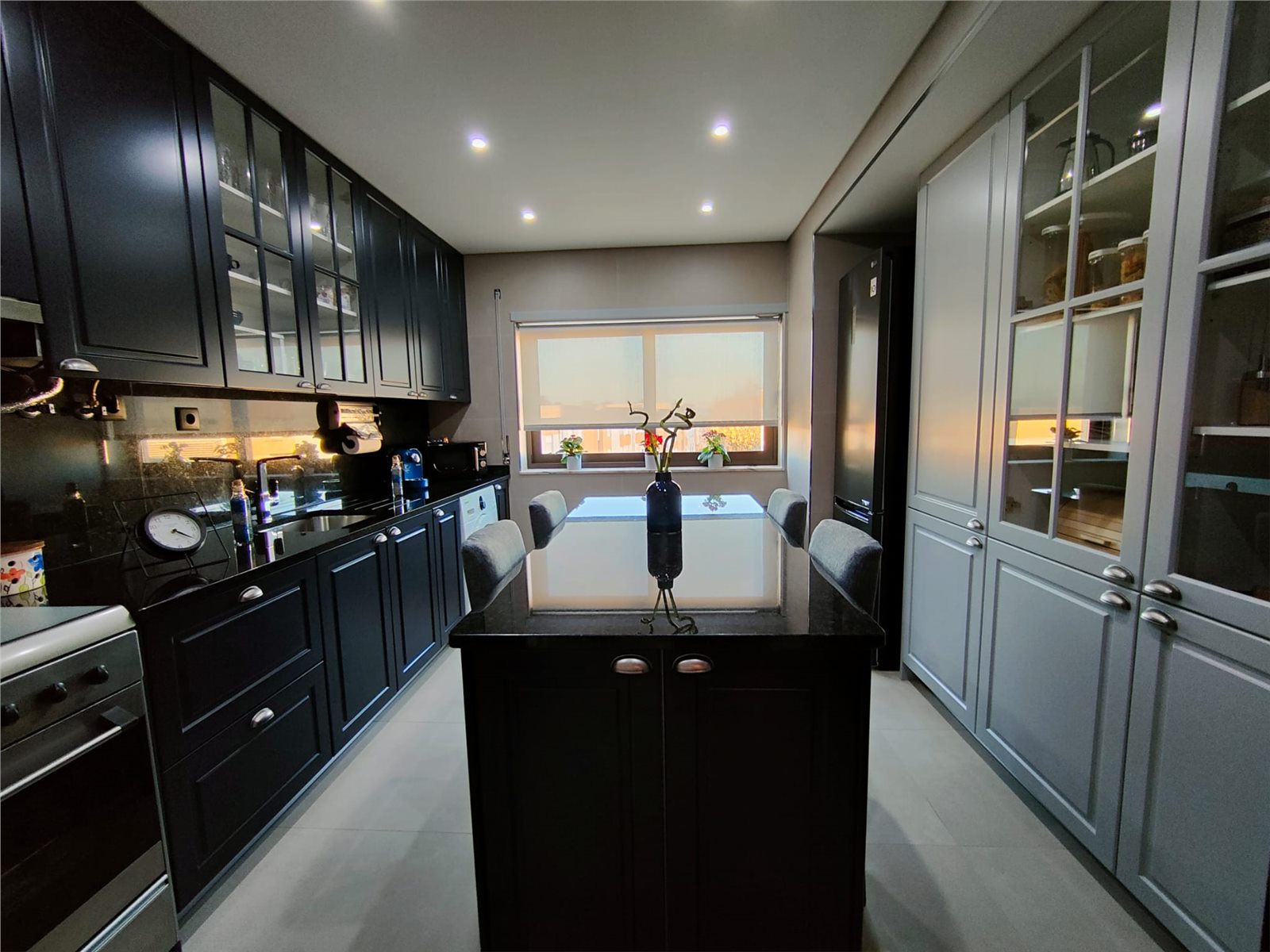 Cozinha renovada com armários escuros, ilha central e boa iluminação